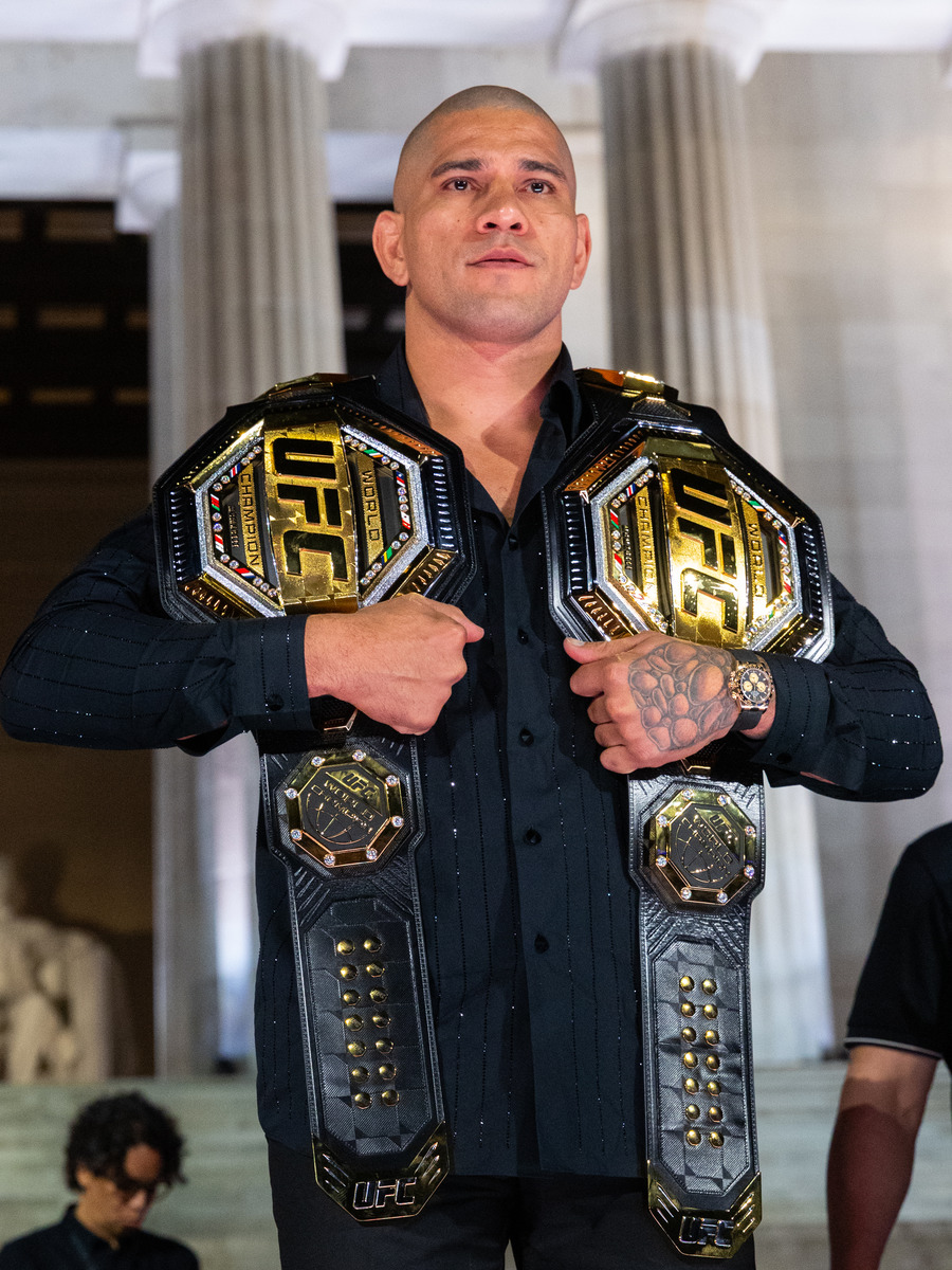 อเล็กซ์ เปเรรา ถือเข็มขัดแชมป์โลก UFC สองเส้นพาดไหล่ ยืนอยู่หน้าเสาของอนุสรณ์สถานลินคอล์น